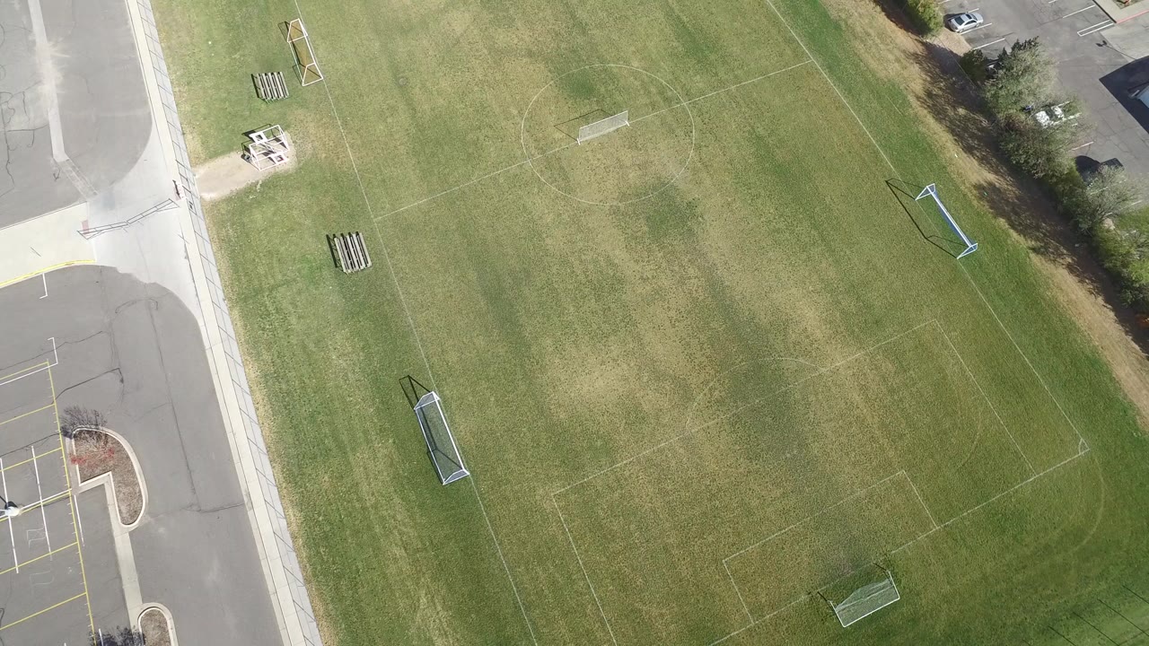 Overhead view of a green football field beside roads and parking.