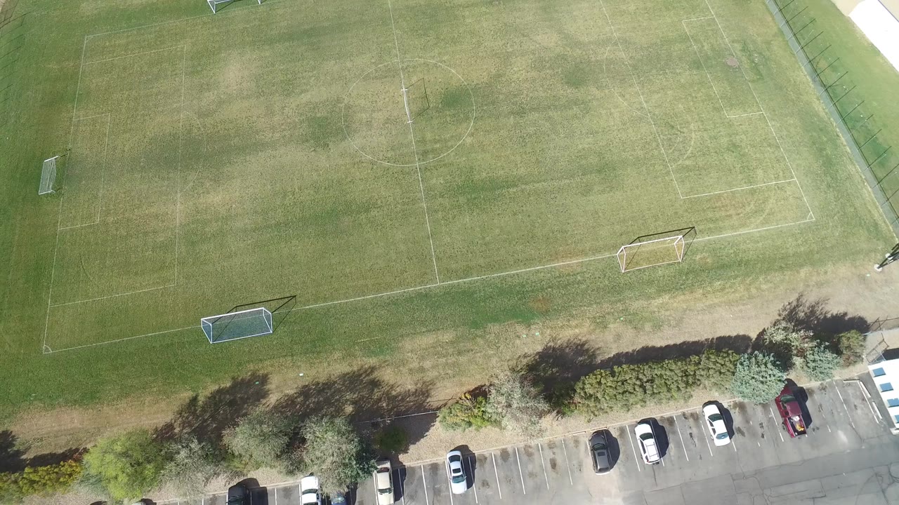 Drone view of soccer field edge and parked cars