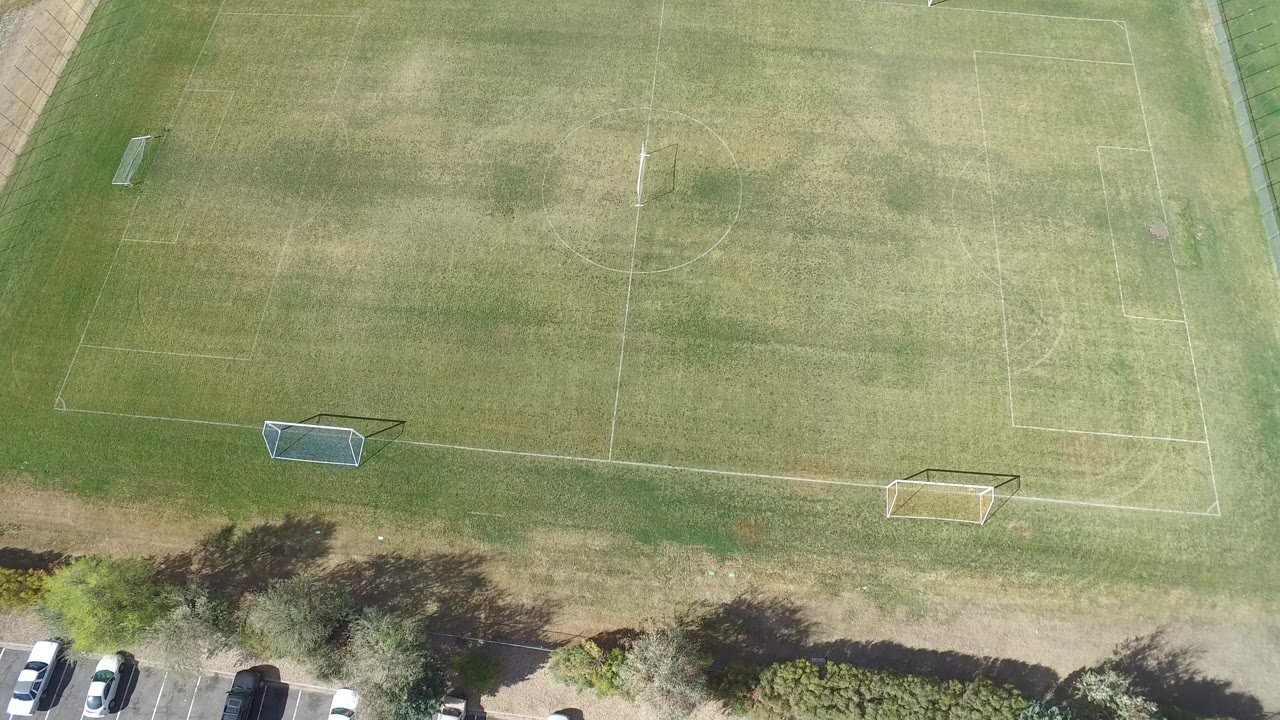 Overhead frame in Hidden Lake, Colorado showing a marked grass sports field, goals, trees, and parked cars along the lower edge, with no visible people.