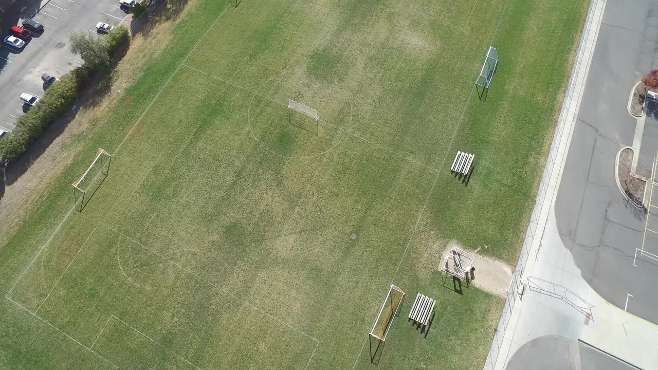 Aerial frame of soccer goals and benches on a grass field.