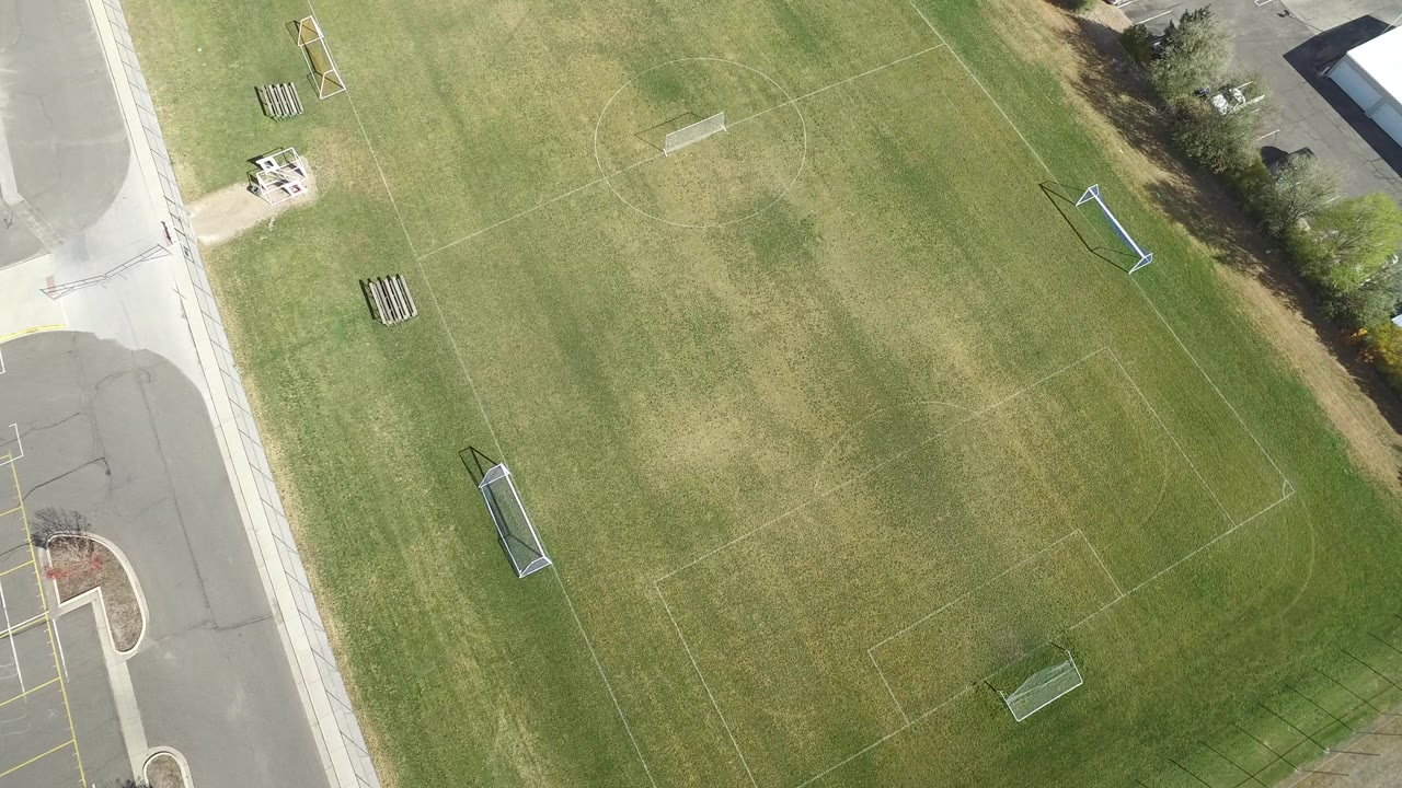 Overhead Hidden Lake, Colorado frame showing the central grass area, two small goals, pale field markings, road edges, and no visible people.