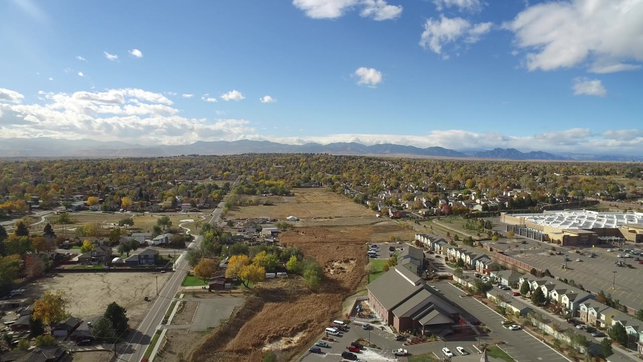 Second aerial frame over Hidden Lake, Colorado, with the road grid and brown open land centered below the mountain horizon, and no visible people.