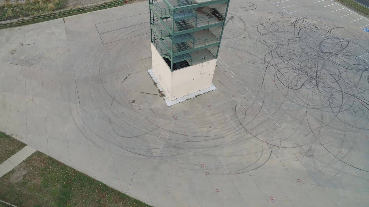 Overhead view of a green ramp structure on a concrete pad with tire marks.