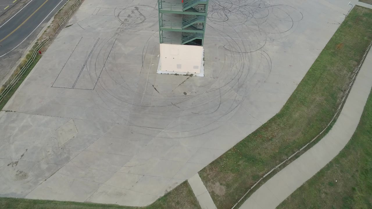 Hidden Lake, Colorado aerial frame with the green metal structure near the top, circular tire marks on the concrete, a grass divider, and no visible people.