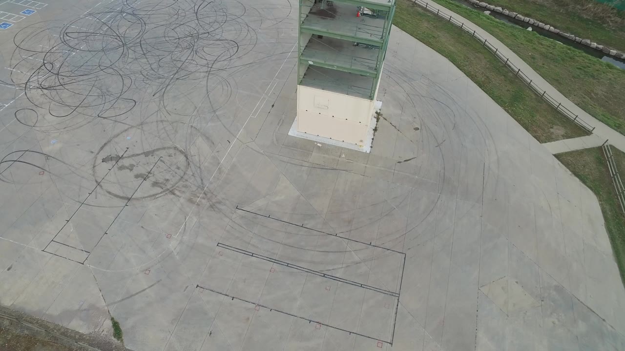 Aerial view in Hidden Lake, Colorado with the green-column structure near the top edge, tire arcs and drawn floor lines across the concrete, and no visible people.