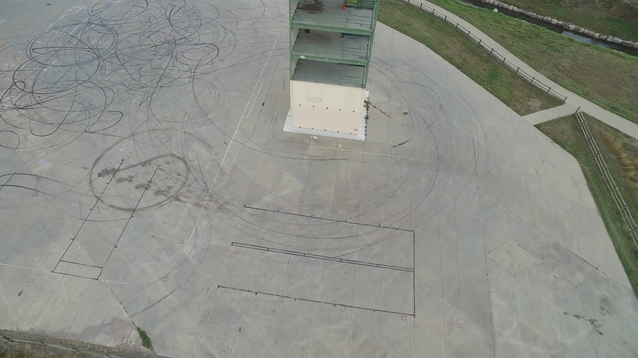 Drone-style overhead view of construction pavement, grass strip, and building frame