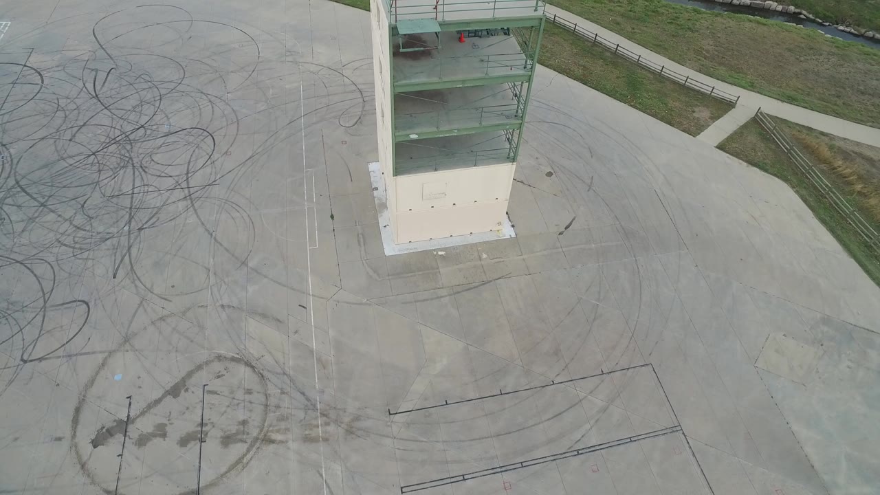 Overhead view of a white tower beside empty concrete and tire marks.