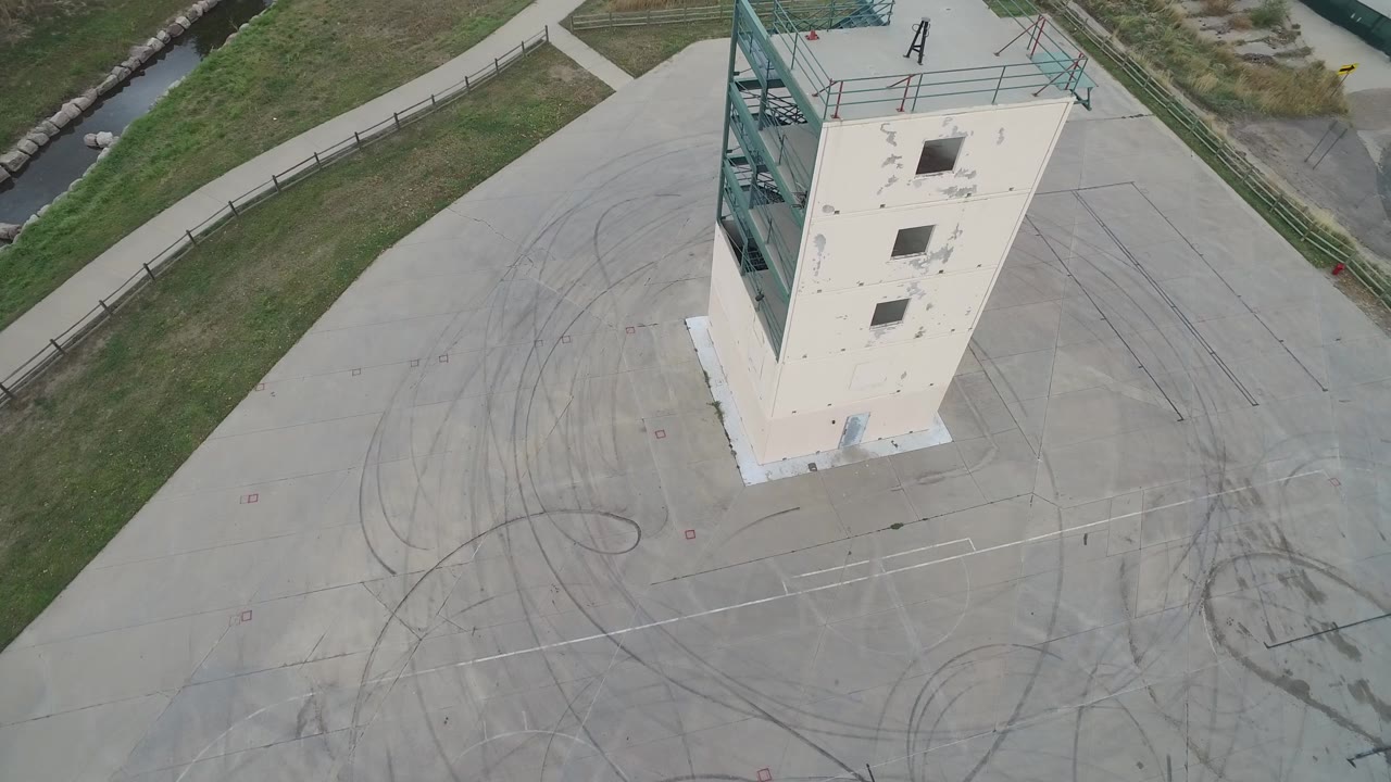 Top-down frame of a tall building near grass and curved tire streaks.