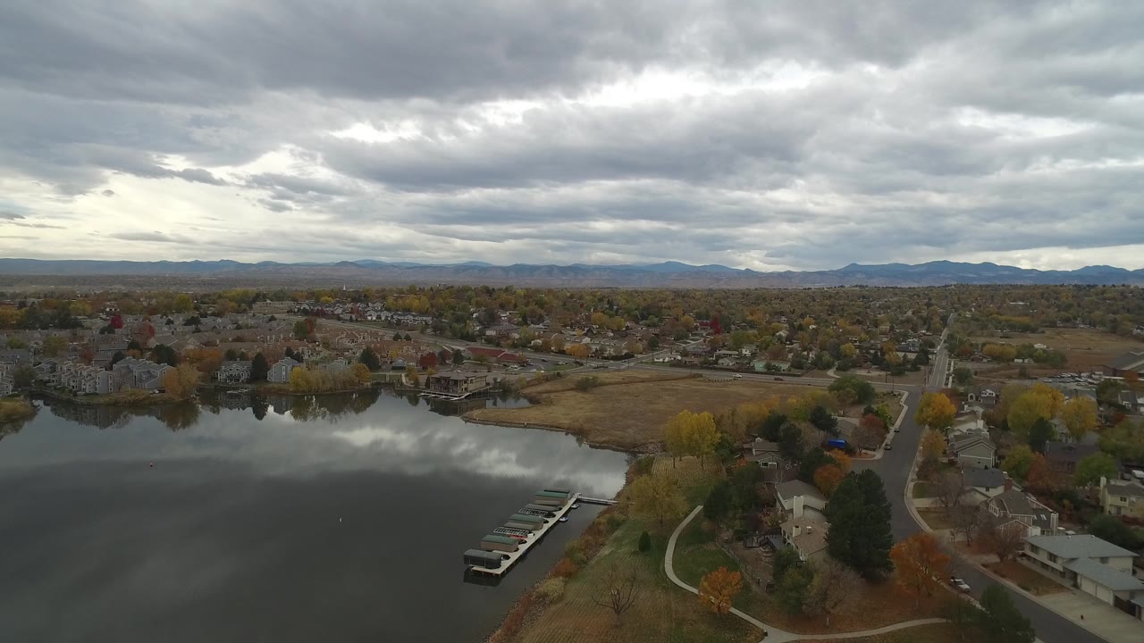 Aerial view of a lake beside homes under gray clouds.