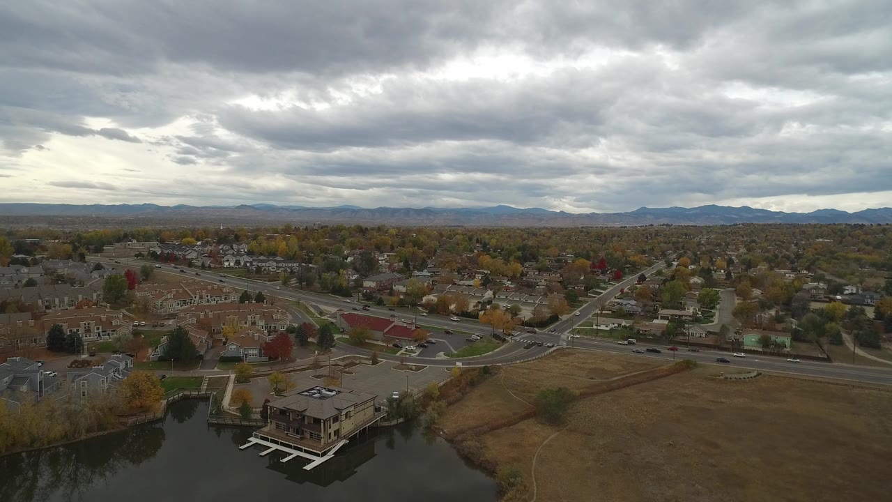 High aerial view of lakefront homes, roads, neighborhoods, and cloudy sky.