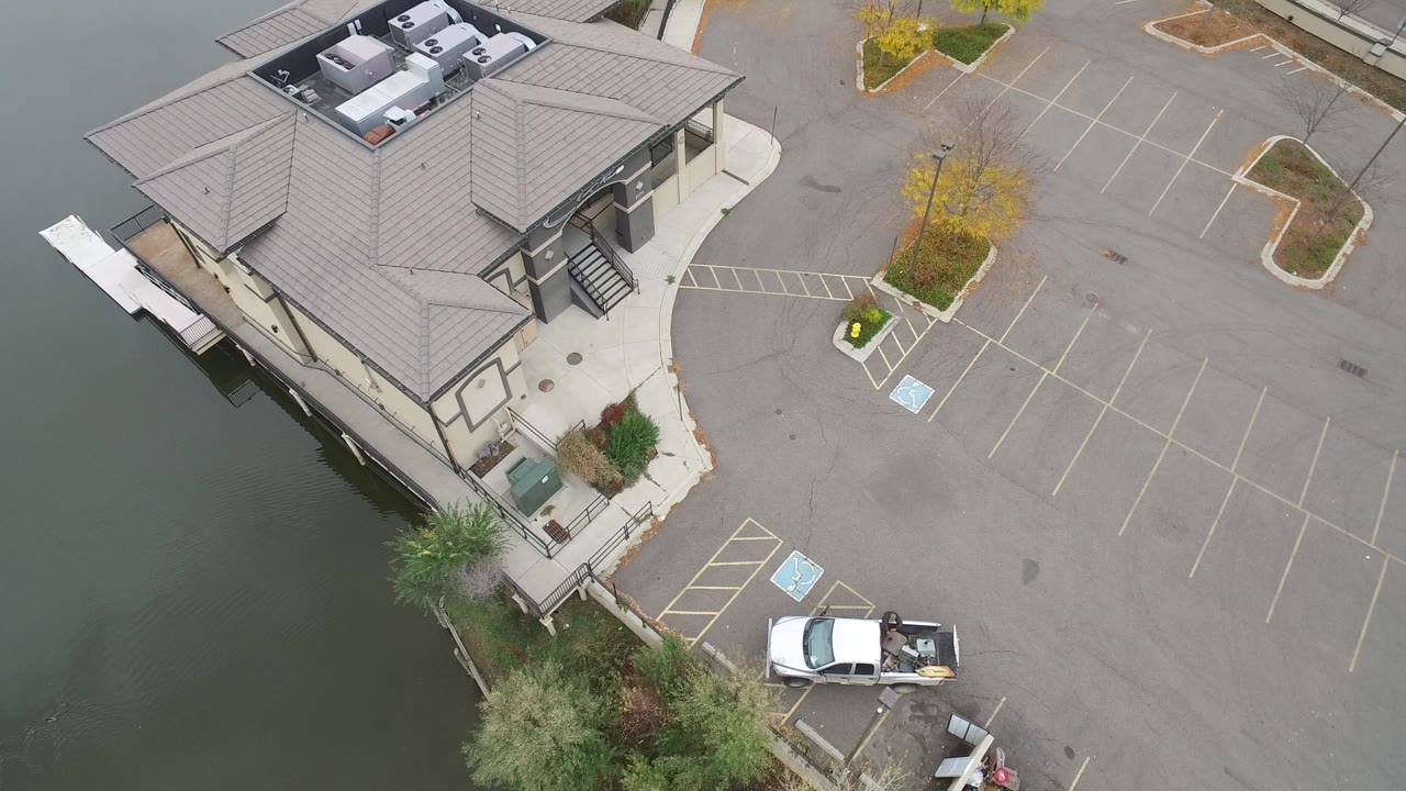 High-angle view of a lakeside business building and mostly empty parking lot.