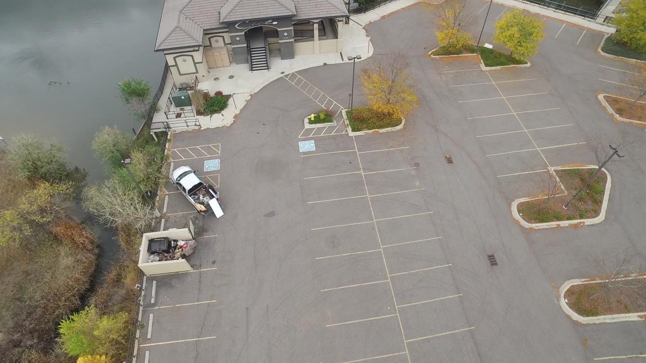 High-angle view of a lakeside parking lot with a white van and building.