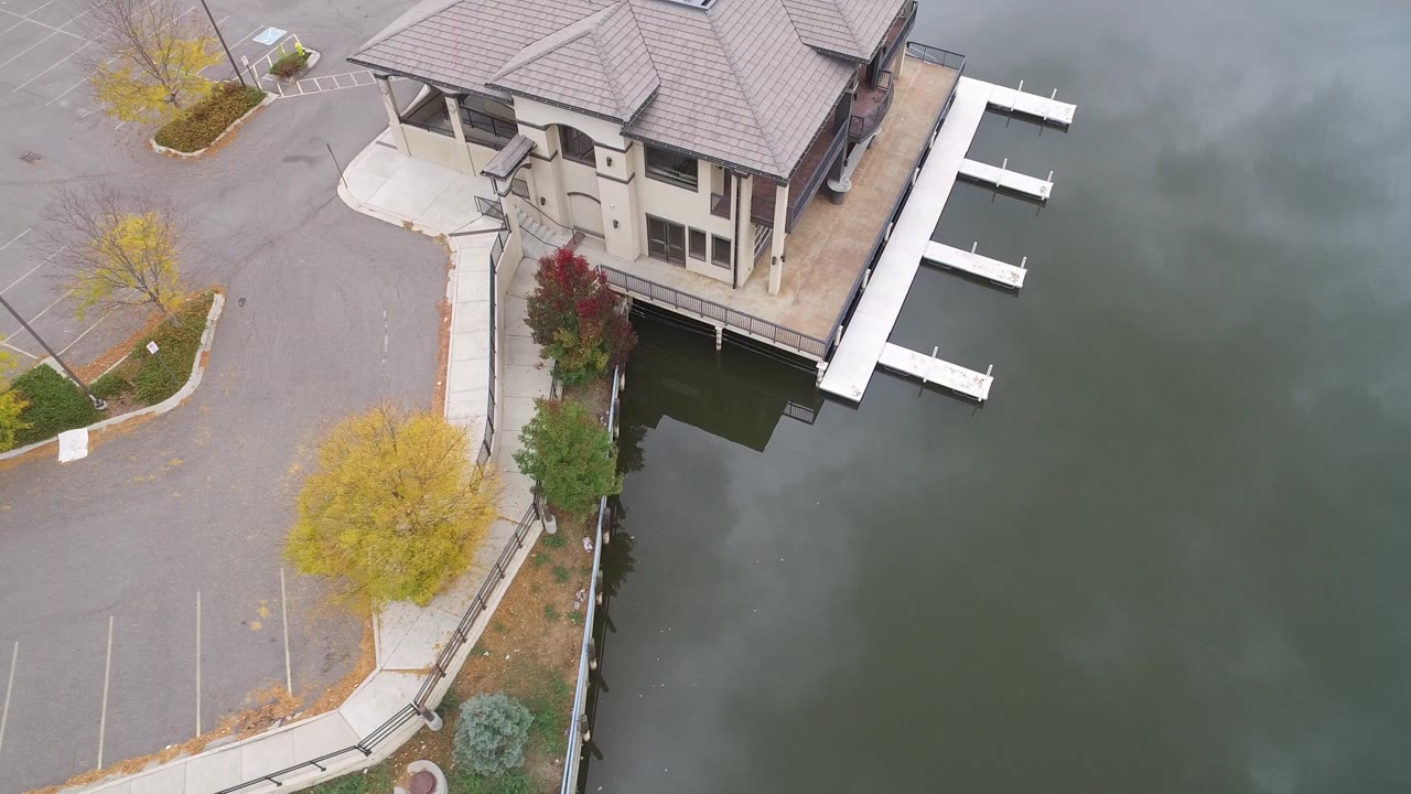High aerial view of a lakeside house with a white dock and parking area.