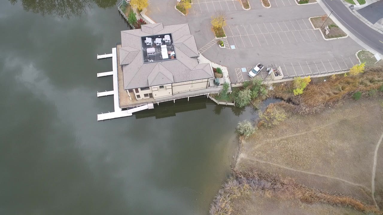 Hidden Lake, Colorado aerial frame with the building slightly left of center, docks reaching into the water, a pale parking lot above, and no visible people.