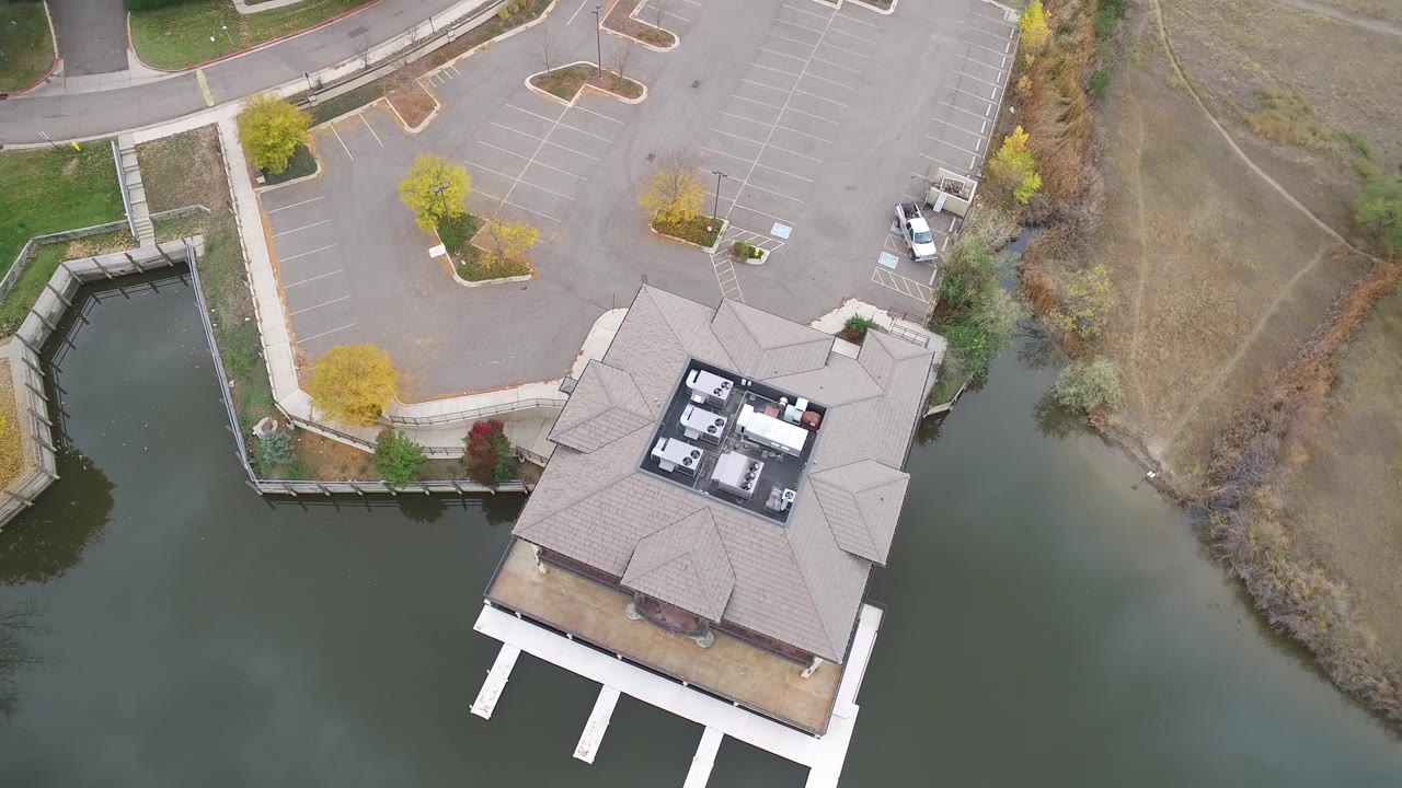 Hidden Lake, Colorado aerial frame with the building centered lower in view, white supports over the water, empty parking spaces above, and no visible people.