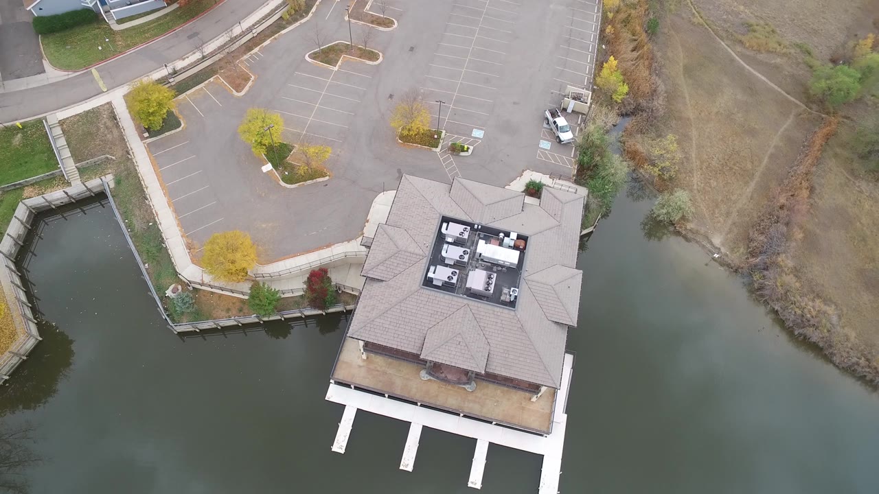 High drone angle over a lakeside building and curved shoreline.