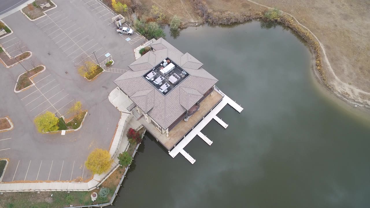Overhead view of a marina boat house, docks, parking lot, and lake water.