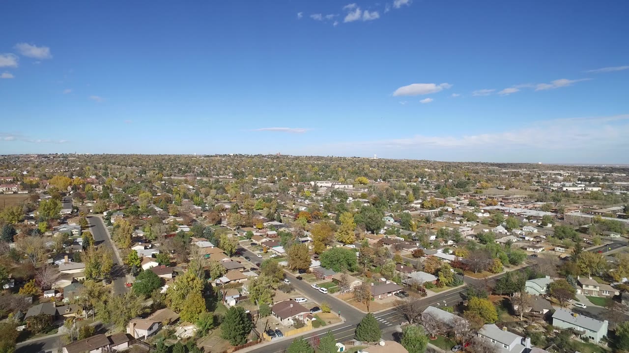 Suburban neighborhood rooftops and roads spread toward a low horizon