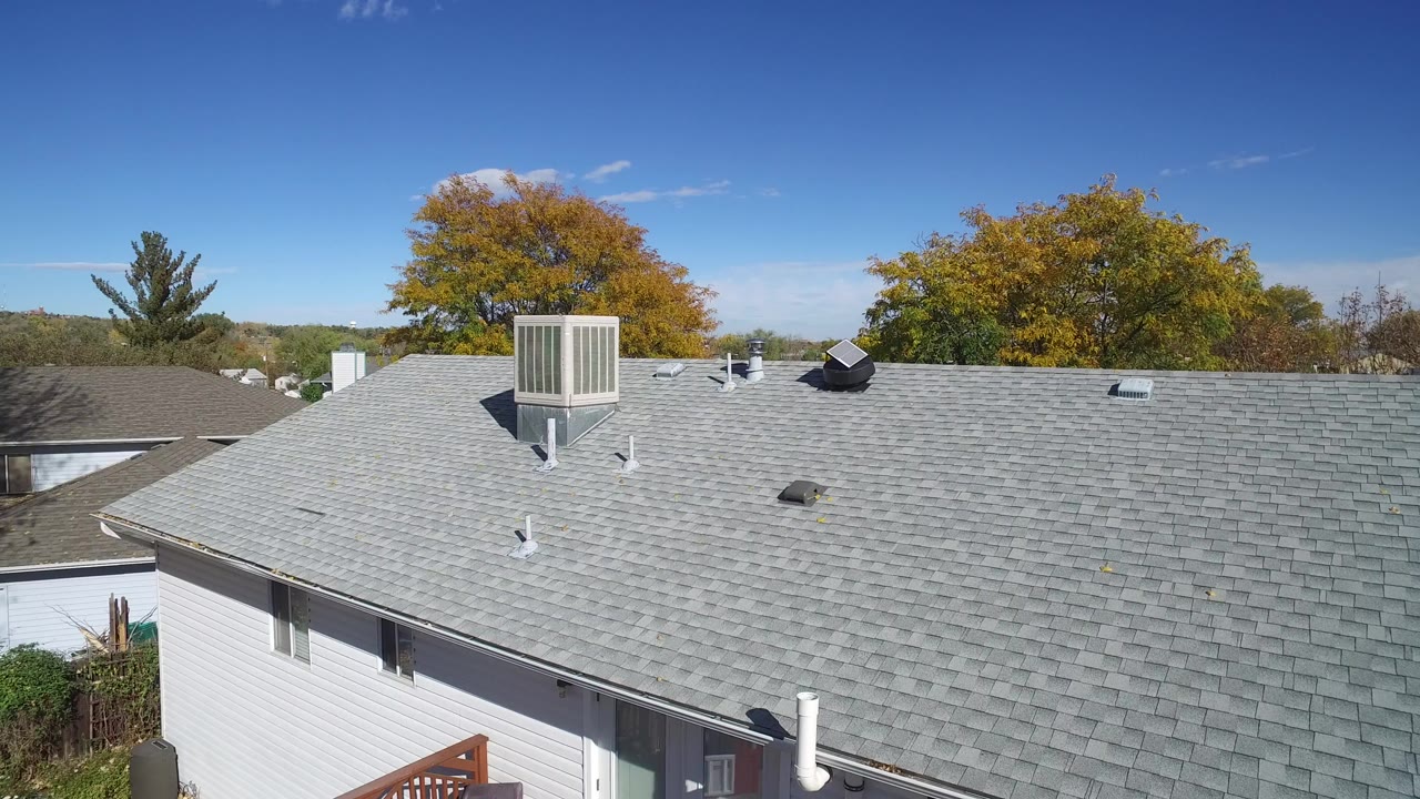 Gray shingle roof with rooftop vent above a light-sided home