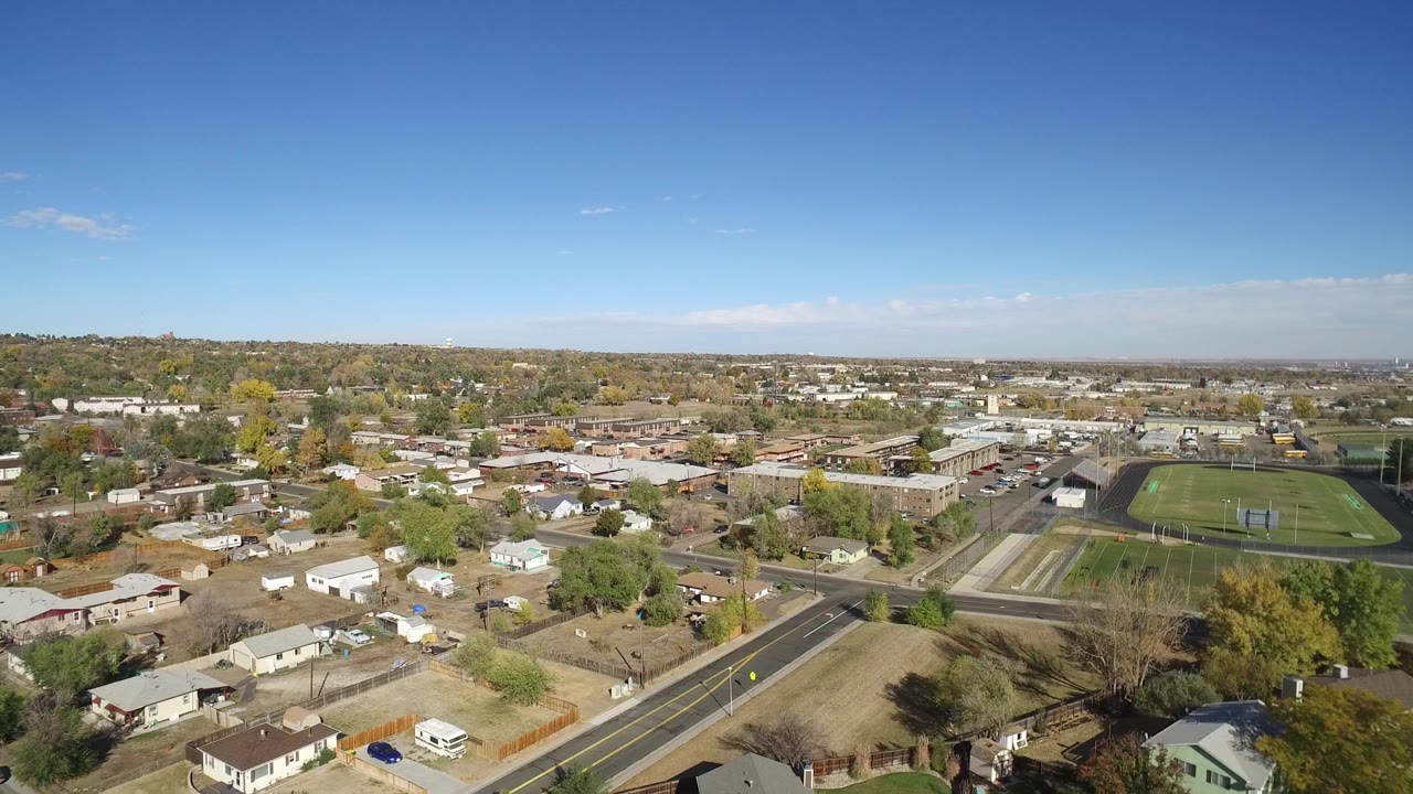 Aerial view of suburban homes, roads, trees, and an athletic field.