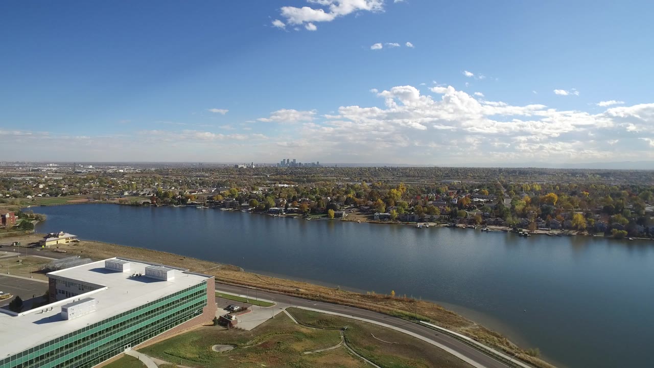 Aerial view of a modern building beside a lake under a blue sky.