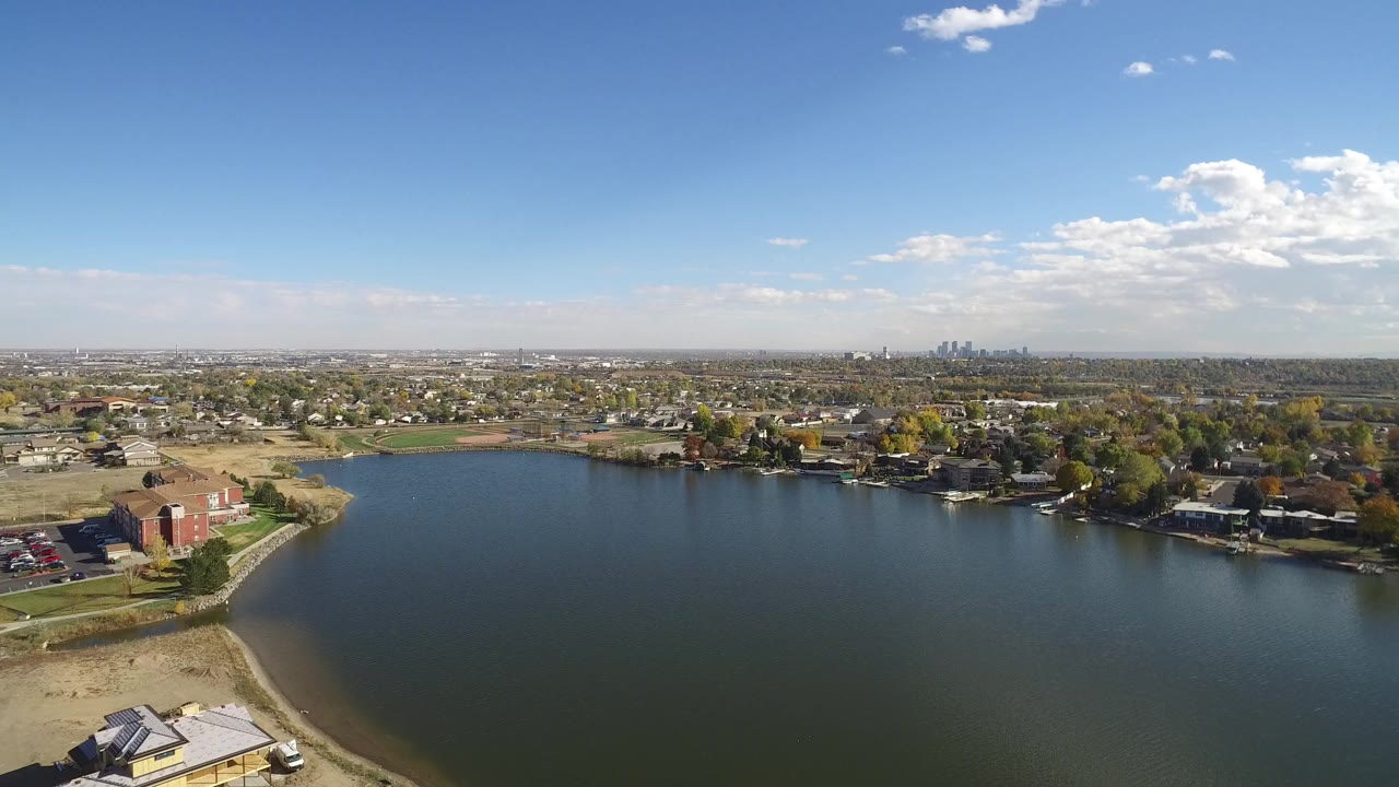 Aerial view over a lake with shoreline homes and distant skyline.