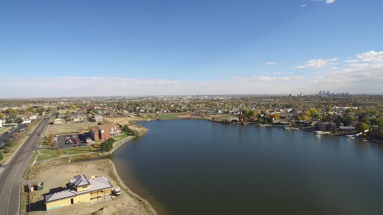 Aerial view of a road beside a lake with houses and distant skyline