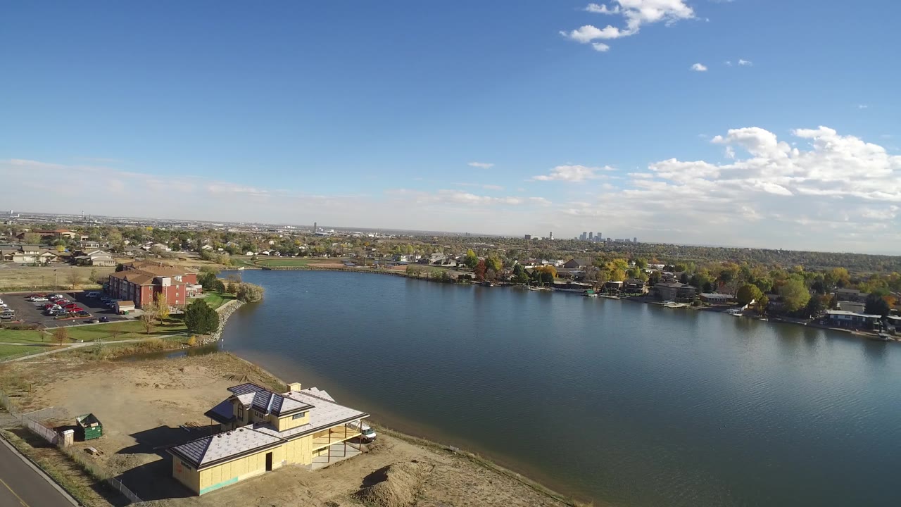 Hidden Lake, Colorado appears from above with more open water centered in frame, a roof and bare shoreline below, houses along the opposite bank, and no visible people.