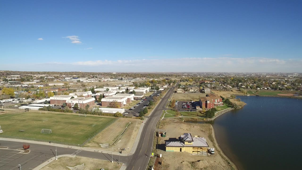 Aerial view of lake, road, grass fields, and low buildings