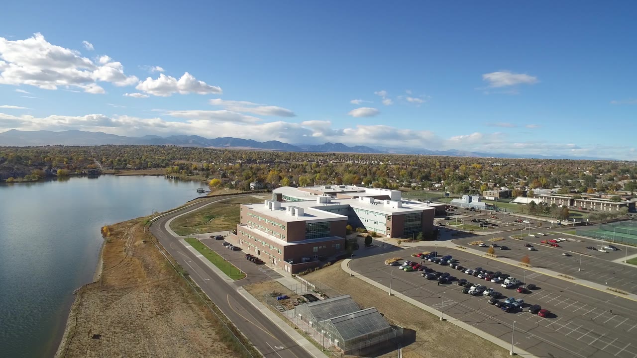 Aerial view of an industrial or institutional complex near water and sports fields.