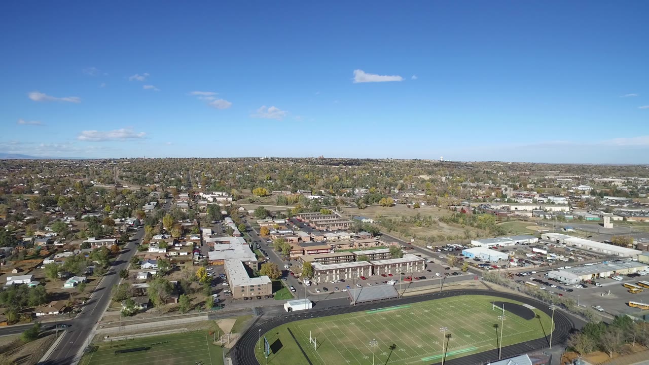 Aerial view of a school football field and track beside suburban streets.