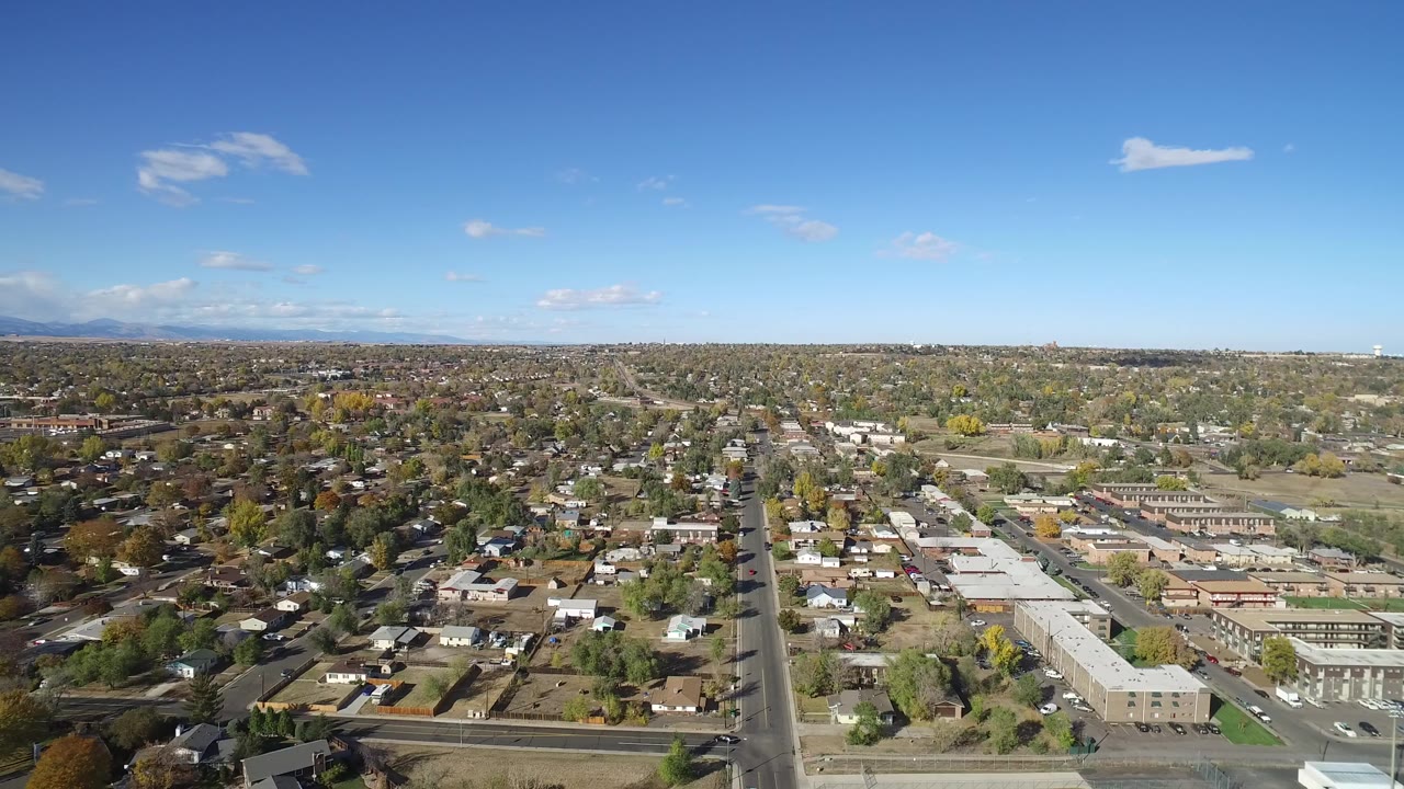 Wide aerial view over residential streets and low buildings under blue sky.