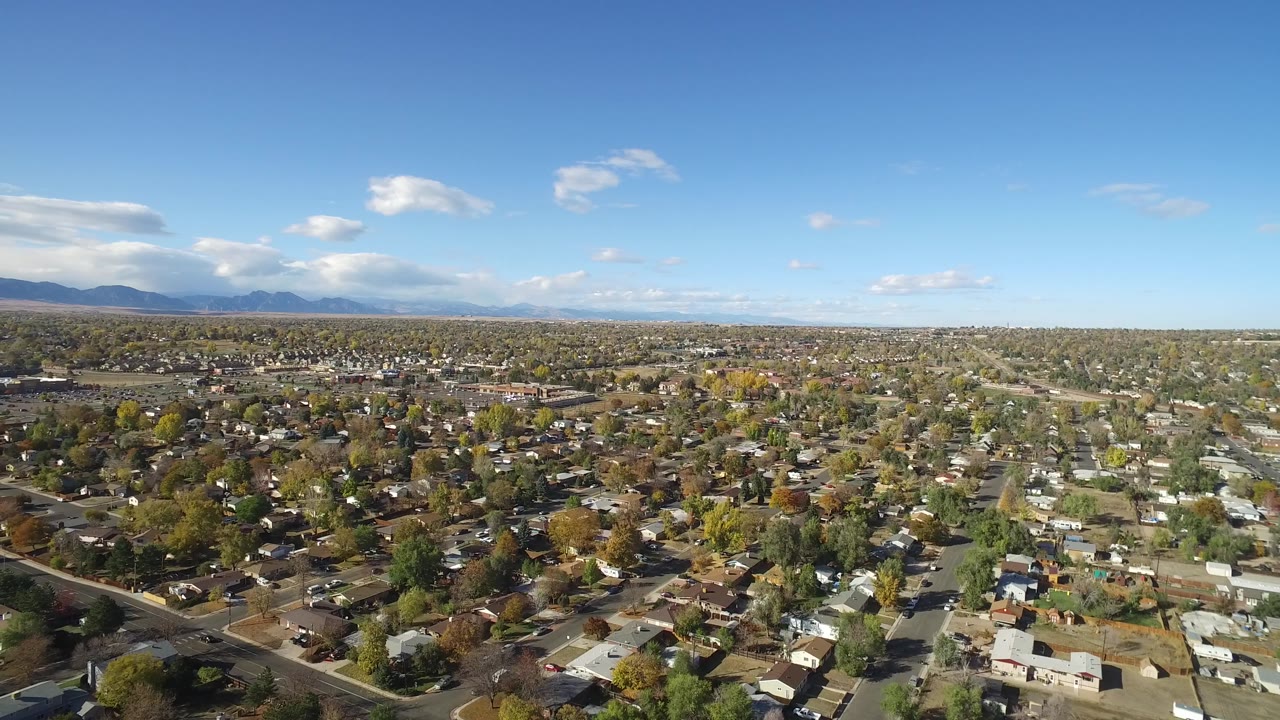 High aerial over a suburban neighborhood with mountains on the horizon.