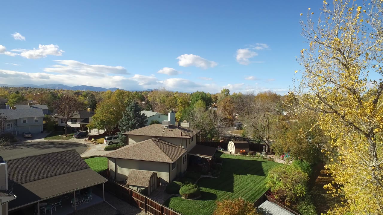 Elevated view over fenced backyards and suburban houses under blue sky.