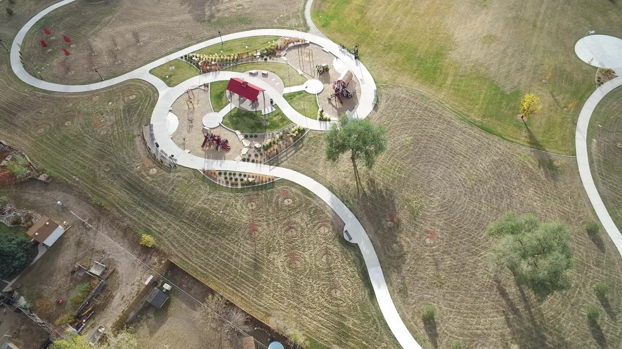 High aerial frame of a landscaped park and surrounding grass.