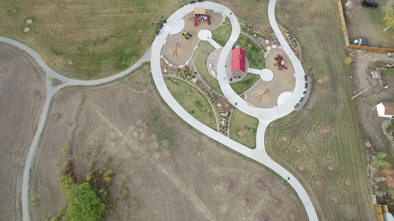 Aerial view of a park complex beside open land and narrow paths.