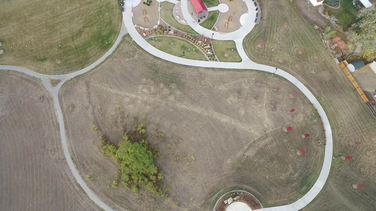 Overhead view of curving paths across mowed open land near a park area.