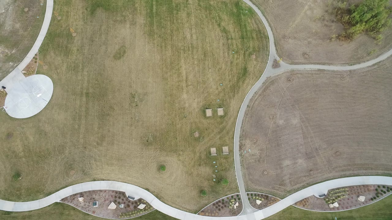 A second overhead moment in Hidden Lake, Colorado shows the grass field centered between sweeping concrete paths, small planted areas, and no visible people.