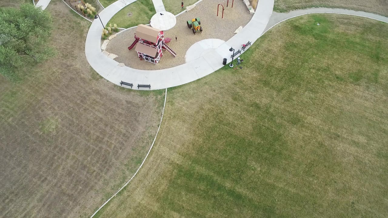 Aerial view of playground equipment beside patchy lawn.