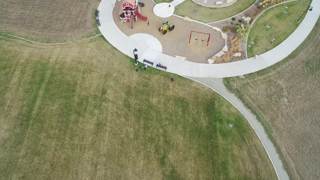 Overhead view of grass, curving paths, and a playground edge.
