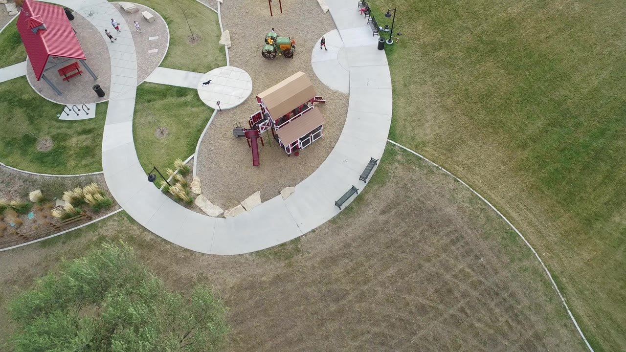 Overhead park path, playground, shelter, grass, and small people.