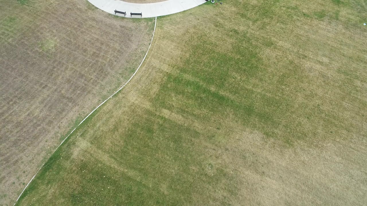 Aerial grass field with diagonal curved path near the top
