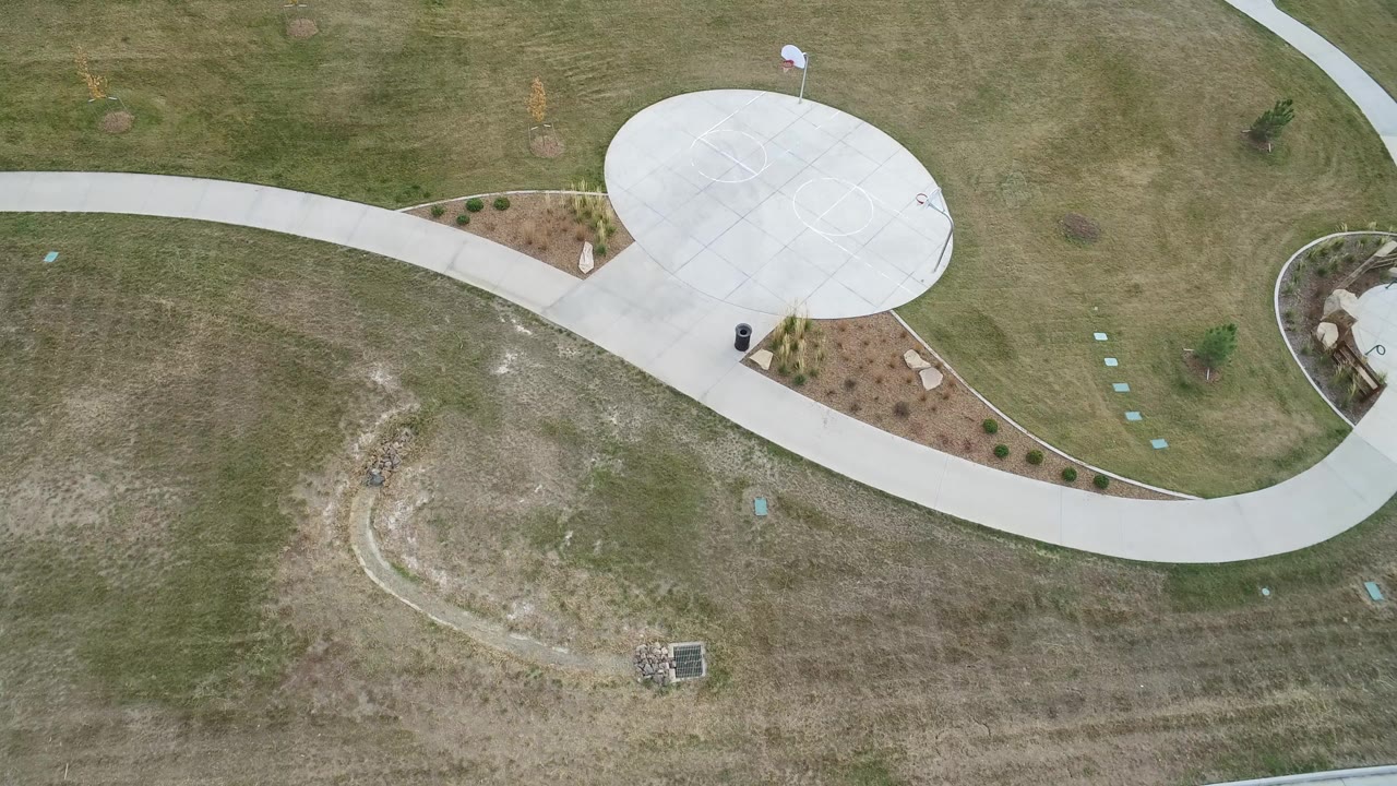 Overhead view of a curved walkway and round concrete pad in grass.