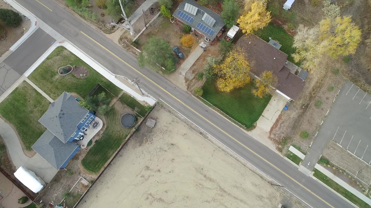 Overhead opening frame in Hidden Lake, Colorado showing a diagonal road, detached homes, sidewalks, lawns, bare lots, and no visible people.