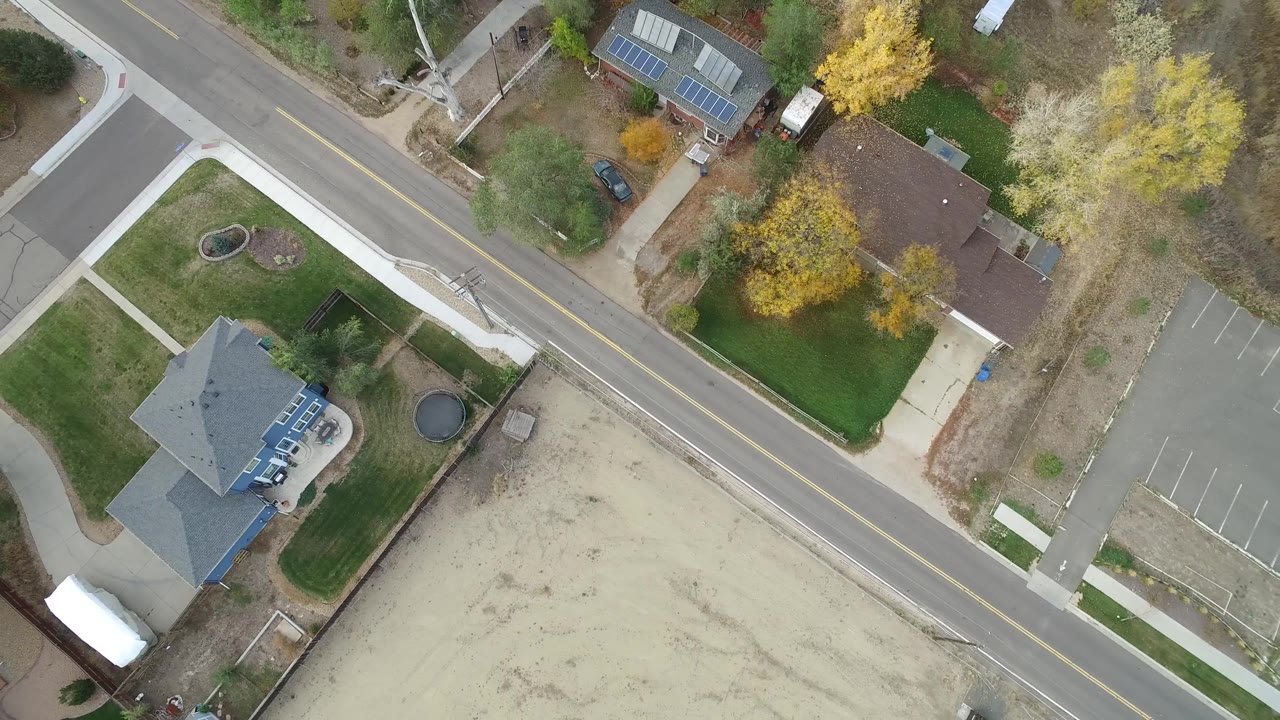 Second frame in Hidden Lake, Colorado shows the road running diagonally past houses with fenced yards, autumn trees, a parking area, and no visible people.