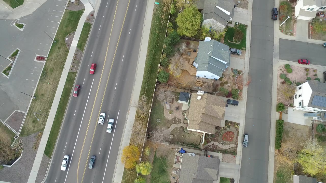Overhead road and suburban houses with cars moving along the lanes.
