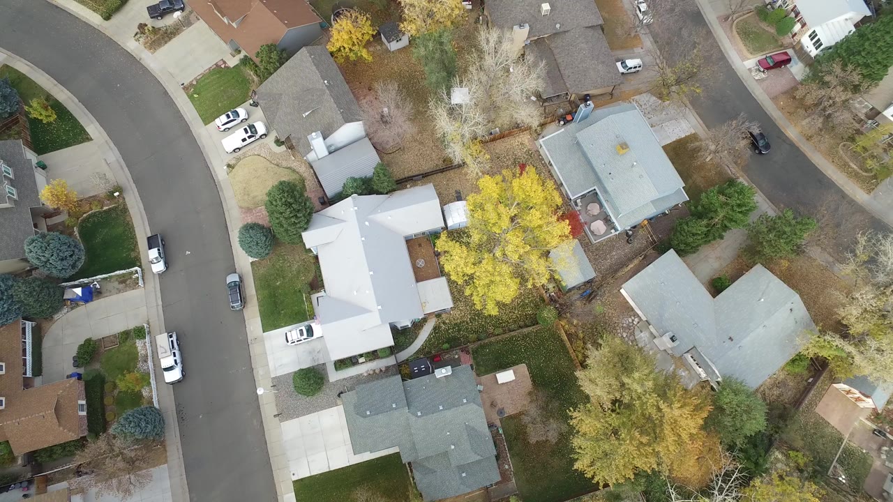 Top-down aerial frame over Hidden Lake, Colorado showing large homes, curved residential roads, driveways, autumn trees, parked cars, and no visible people.