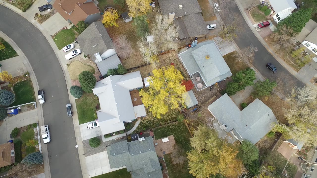 Aerial view of residential blocks with cars and tree cover.
