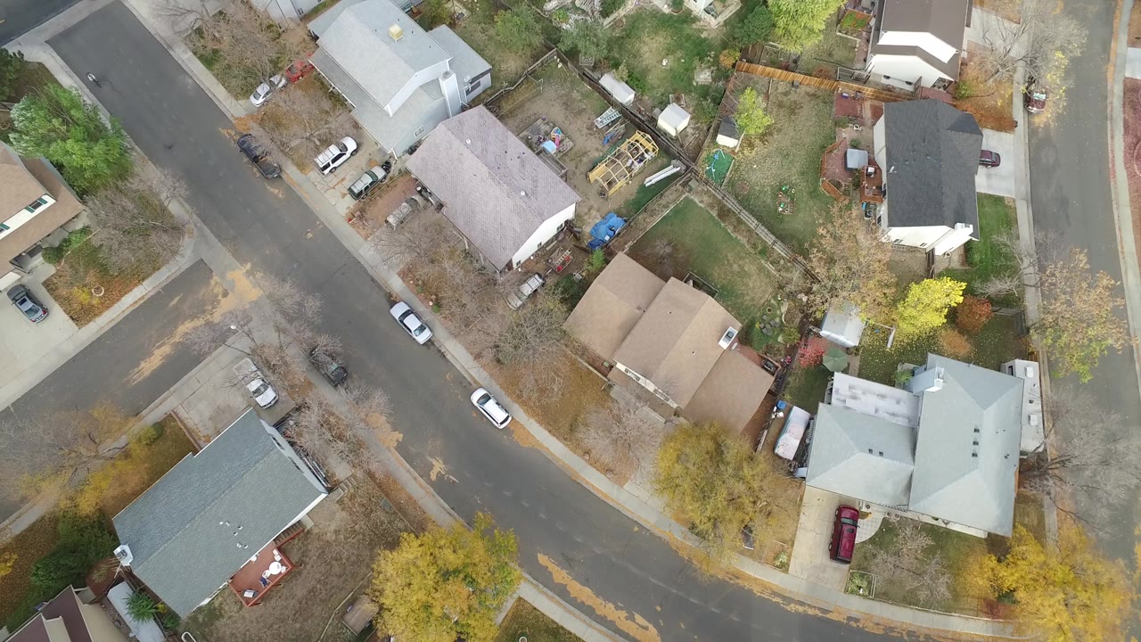 Top-down aerial frame over Hidden Lake, Colorado showing several private homes, fenced yards, parked cars, trees, and curved residential streets with no visible people.