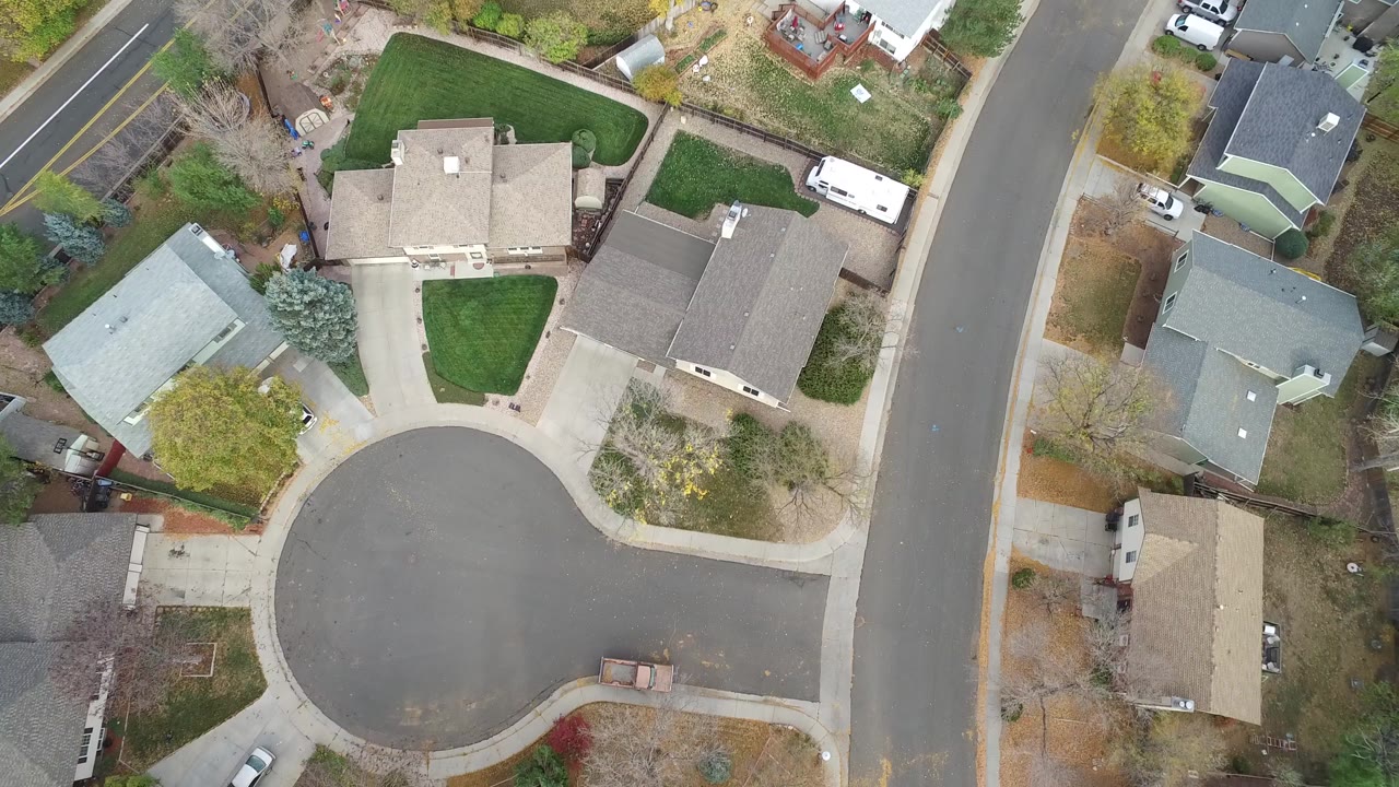 Overhead view of a cul-de-sac with houses, lawns, trees, and a road.